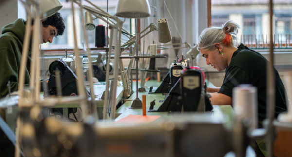 Två textilstuderande arbetar vid sina symaskiner i skolans ateljé